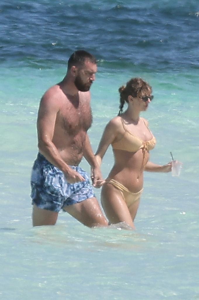 Taylor Swift and Travis Kelce wearing swimsuits in the ocean