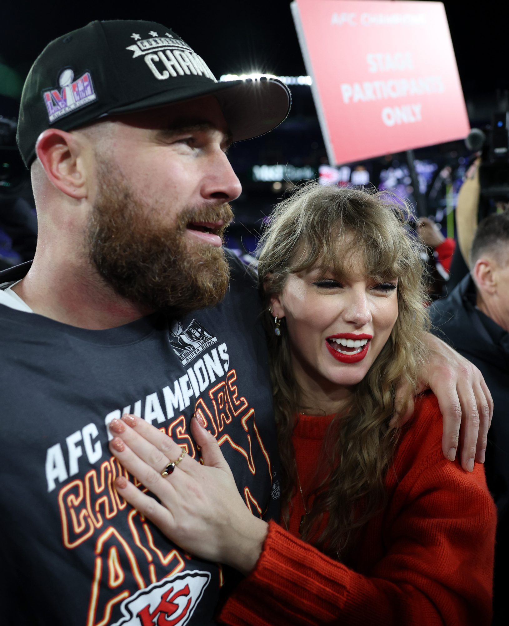 Taylor Swift and Travis Kelce hug each other on the football field.