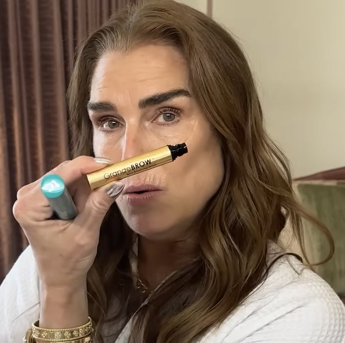 Brooke Shields holding a tube of lash serum