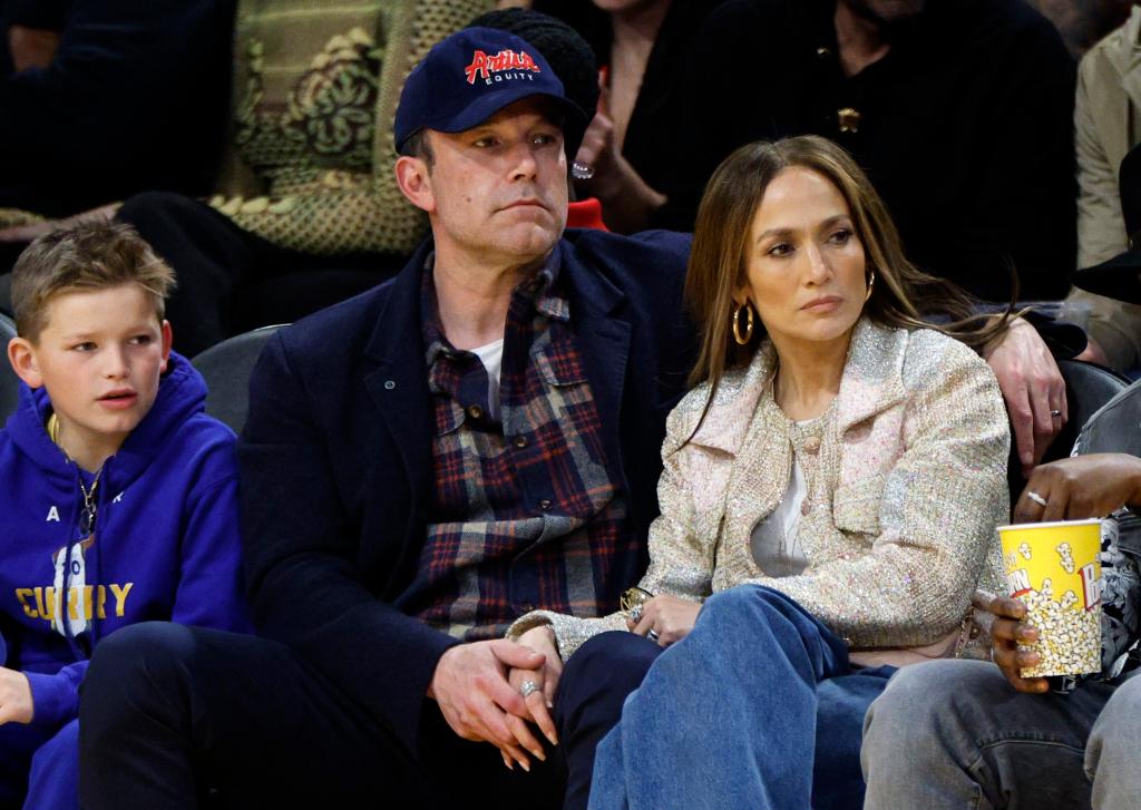 Ben Affleck and his son, Samuel, sitting next to Jennifer Lopez at a basketball game