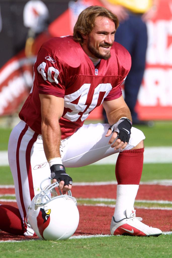 Pat Tillman, in Arizona Cardinals uniform, kneeling on the football field.