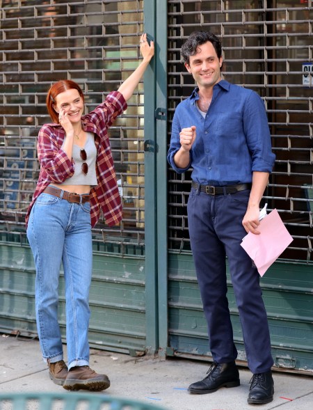 Madeline Brewer and Penn Badgley leaning against a locked storefront gate