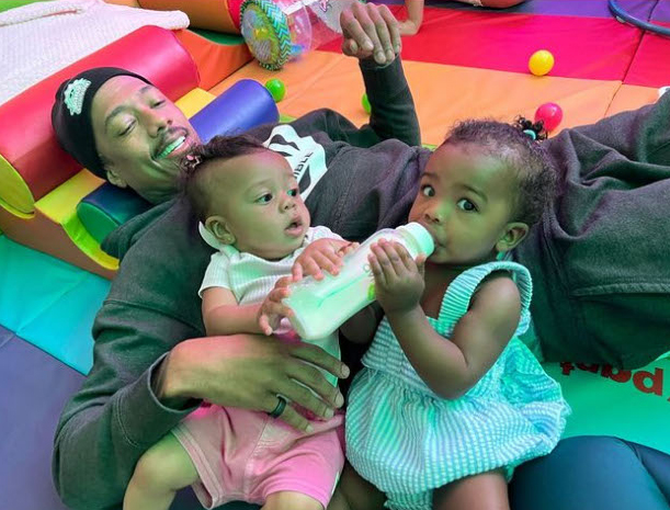 nick cannon lying on a mat with two of his babies