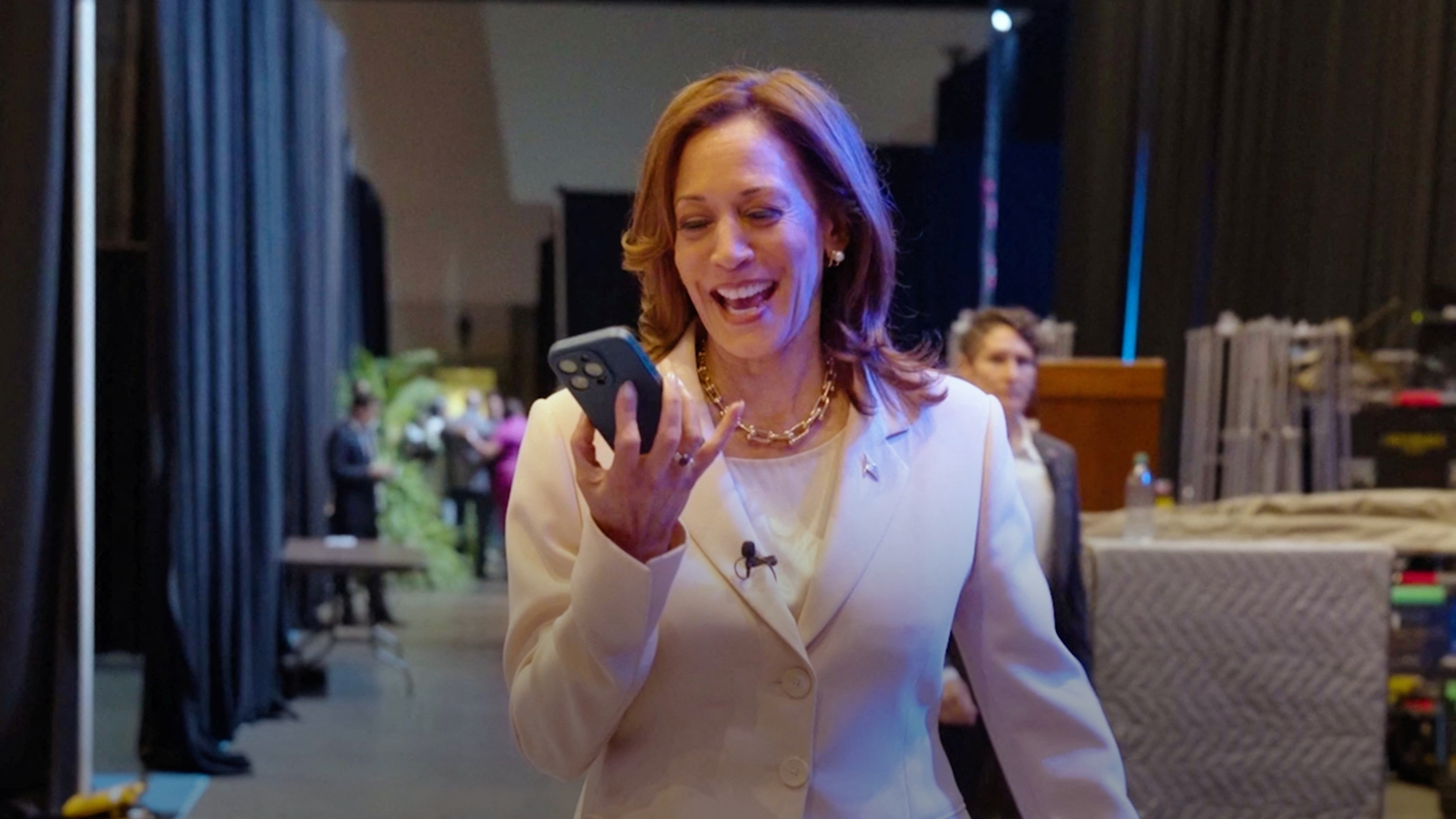 kamala harris smiling as she stares at her phone