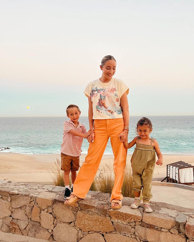 aurora culpo standing on a rock wall with her two kids