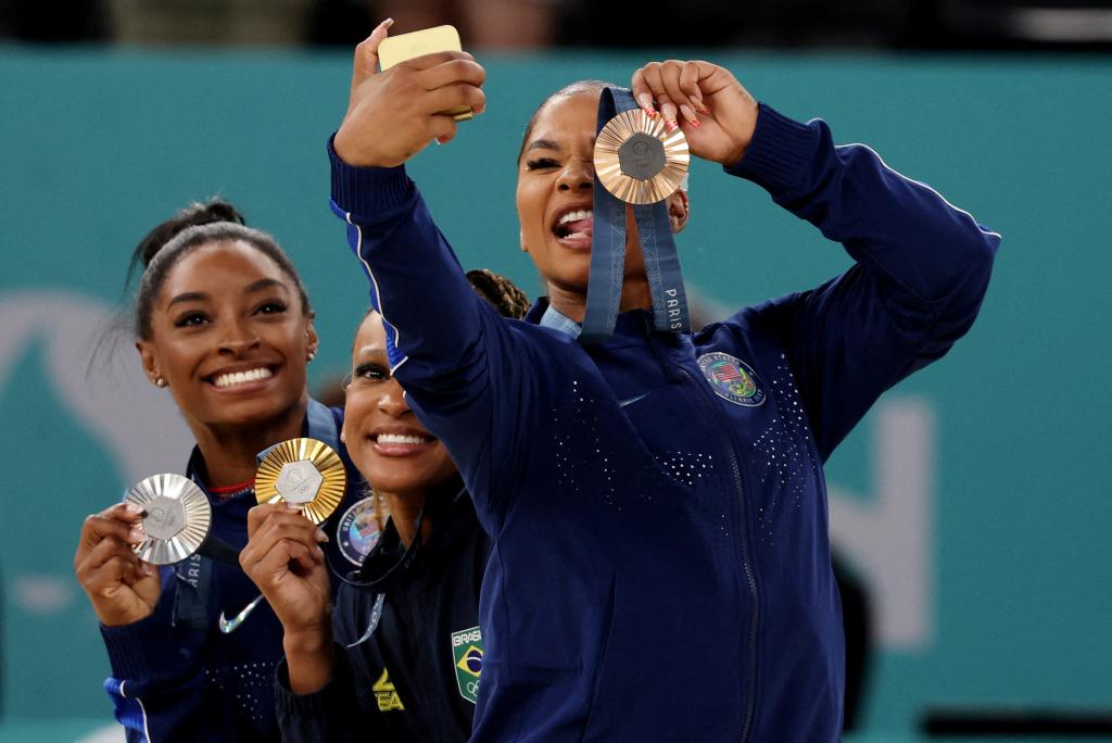 Gold medallist Rebeca Andrade of Brazil celebrates on the podium with silver medallist Simone Biles of United States and bronze medallist Jordan Chiles of United States on Aug. 5.