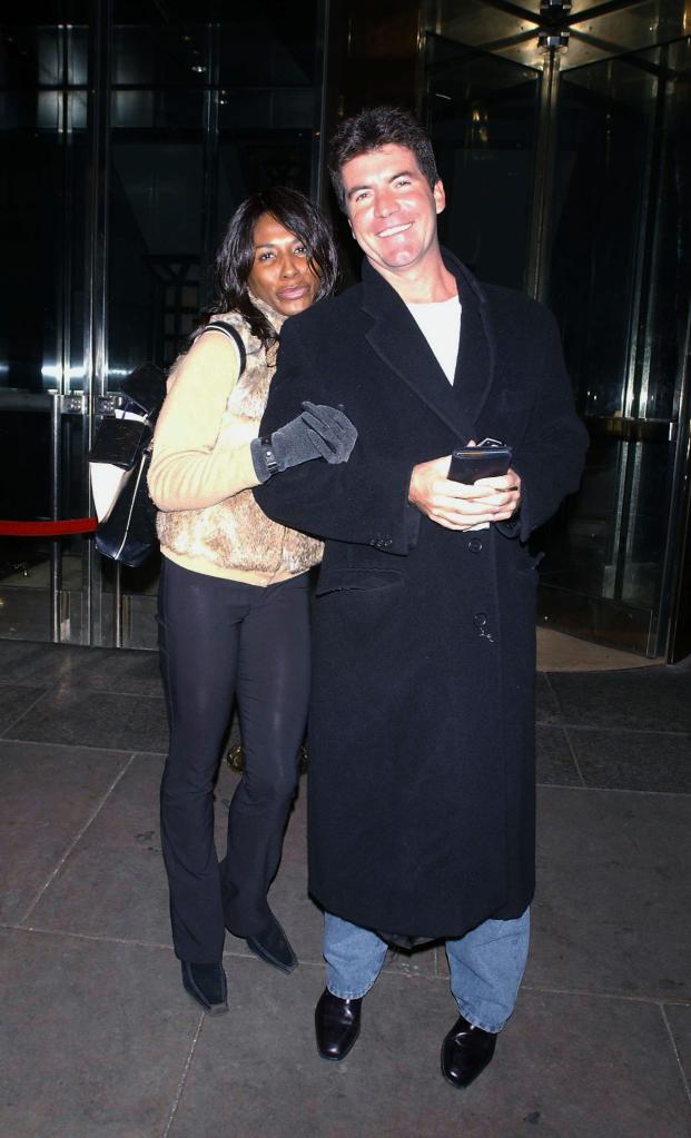 "American Idol" host Simon Cowell walks out of a hotel with 80's pop star Sinitta February 13, 2003 in New York City.