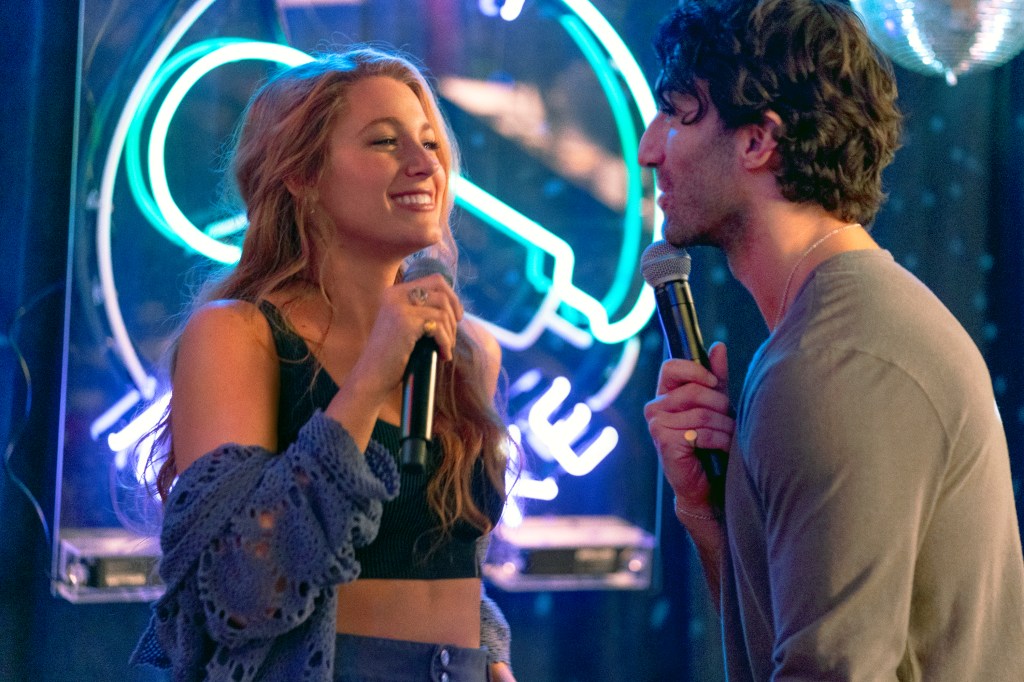 Justin Baldoni and Blake Lively hold microphones.