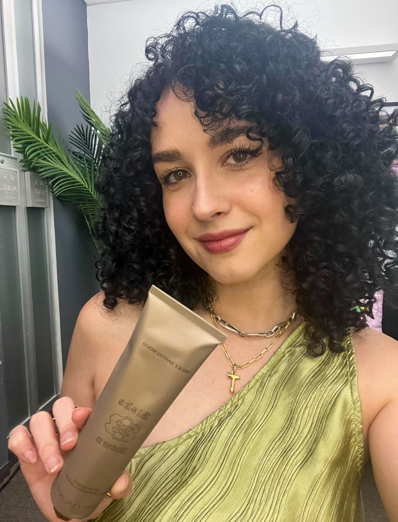 Taylor Valentine holding a bottle of Blake Brown Milky Sandalwood Rich Reset Pre-Shampoo Mask