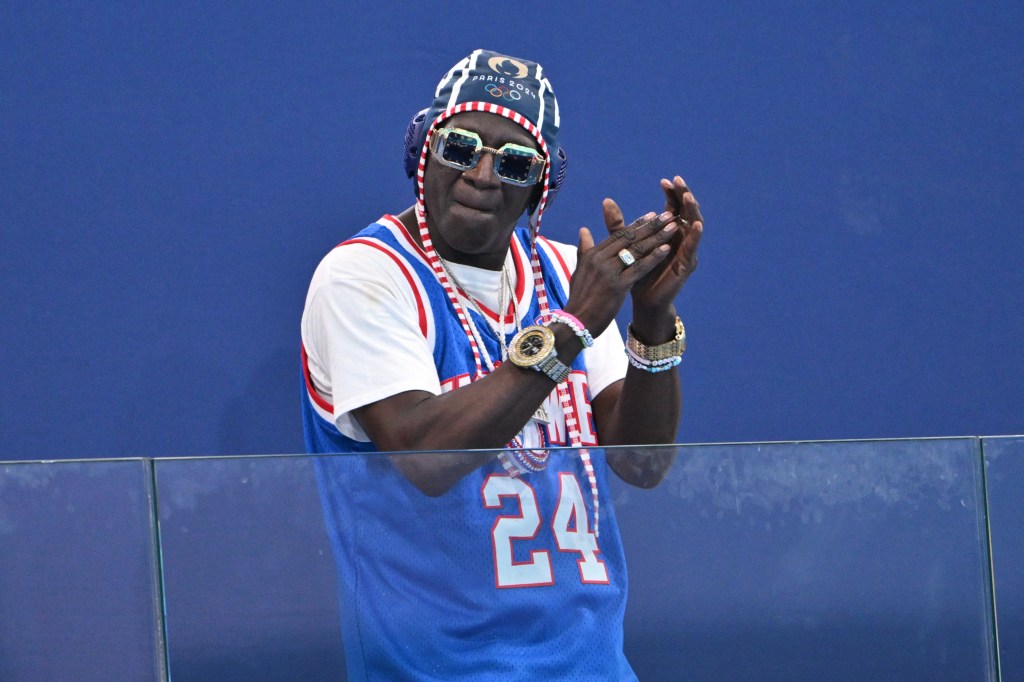 US actor and rapper William Jonathan Drayton Jr. known by his stage name Flavor Flav, gestures before the women's water polo preliminary round group B match between Italy and USA during the Paris 2024 Olympic Games at the Aquatics Centre in Saint-Denis, north of Paris, on July 31, 2024. 