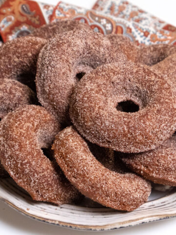 Apple Cake Doughnuts on a plate with a napkin in the background.