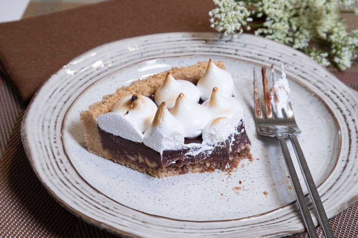 This photo shows the S'Mores Tart partially eaten with the fork on the plate.  