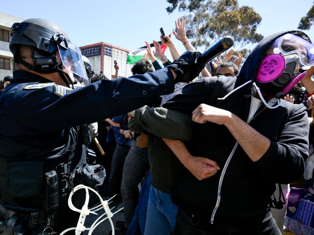 A protester is hit with a baton by a police officer at UC San Diego, May 6, 2024, in San Diego. 