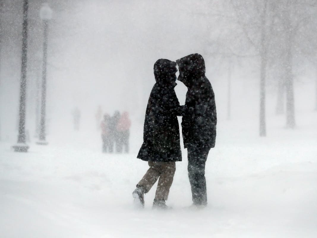 A couple walks through the snow on Boston Common on Saturday in Boston. 