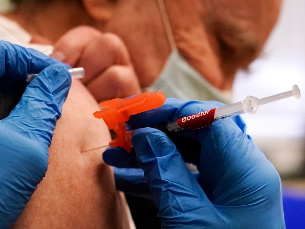 A pharmacist injects a man with a booster dose of the Moderna COVID-19 vaccine during a vaccination clinic in December 2021.