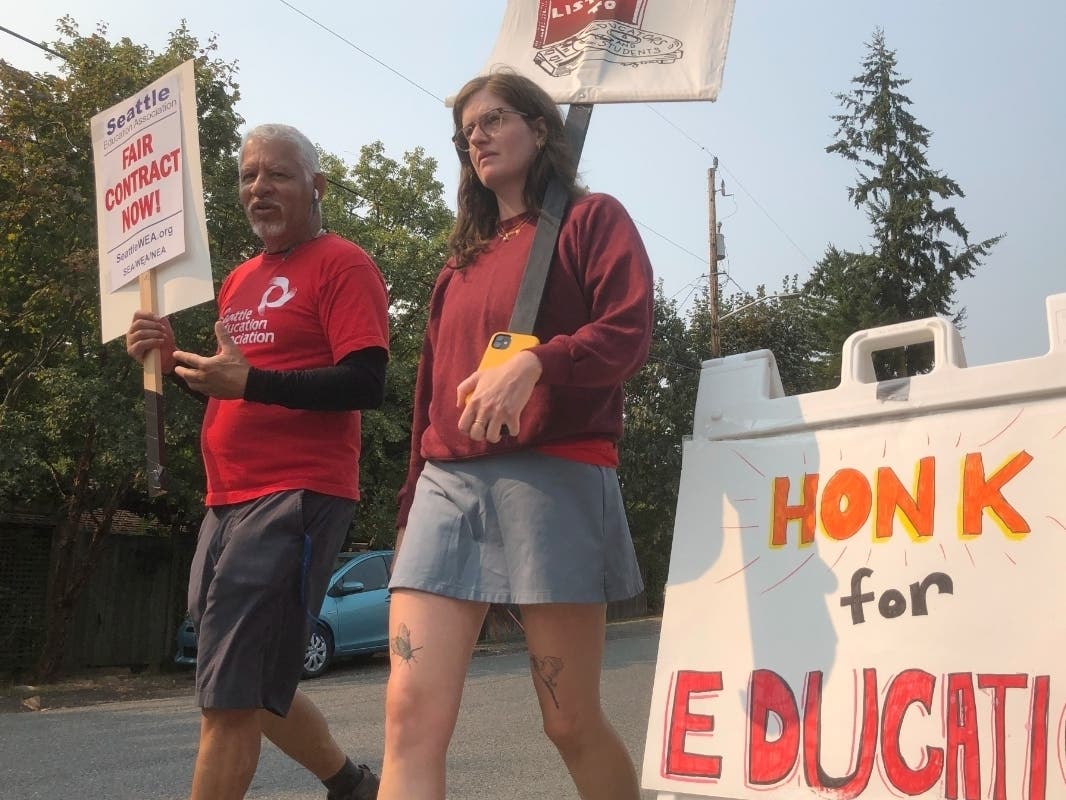 Guillermo Carvajal, a member of the support staff at Northgate Elementary School in Seattle, and Erin Carroll, an occupational therapist there, picket outside the building on the third day of a strike by the Seattle Education Association on Friday, Sept. 