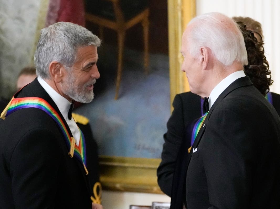  President Joe Biden shakes hands with actor, director and producer George Clooney during the Kennedy Center honorees reception. Clooney is adding his voice to calls for Joe Biden to leave the presidential race.