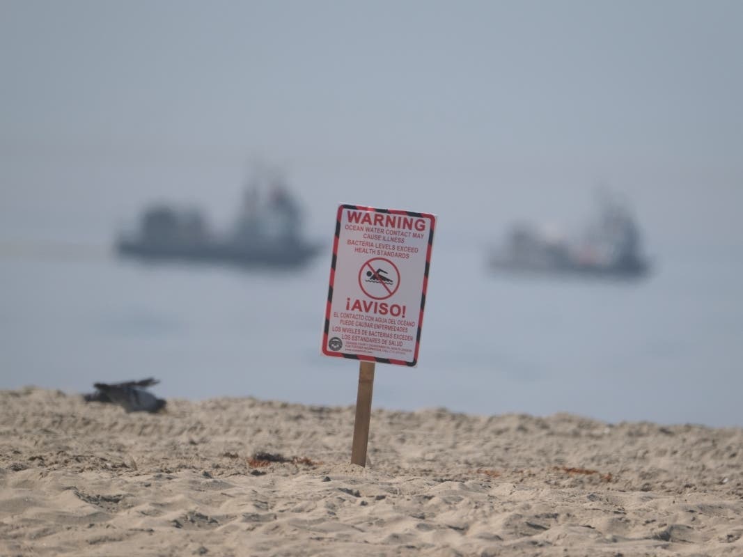 A posted sign warning about water contact may cause illness, is posted by life guards after an oil spill in Huntington Beach, Calif., Sunday, Oct. 3, 2021.