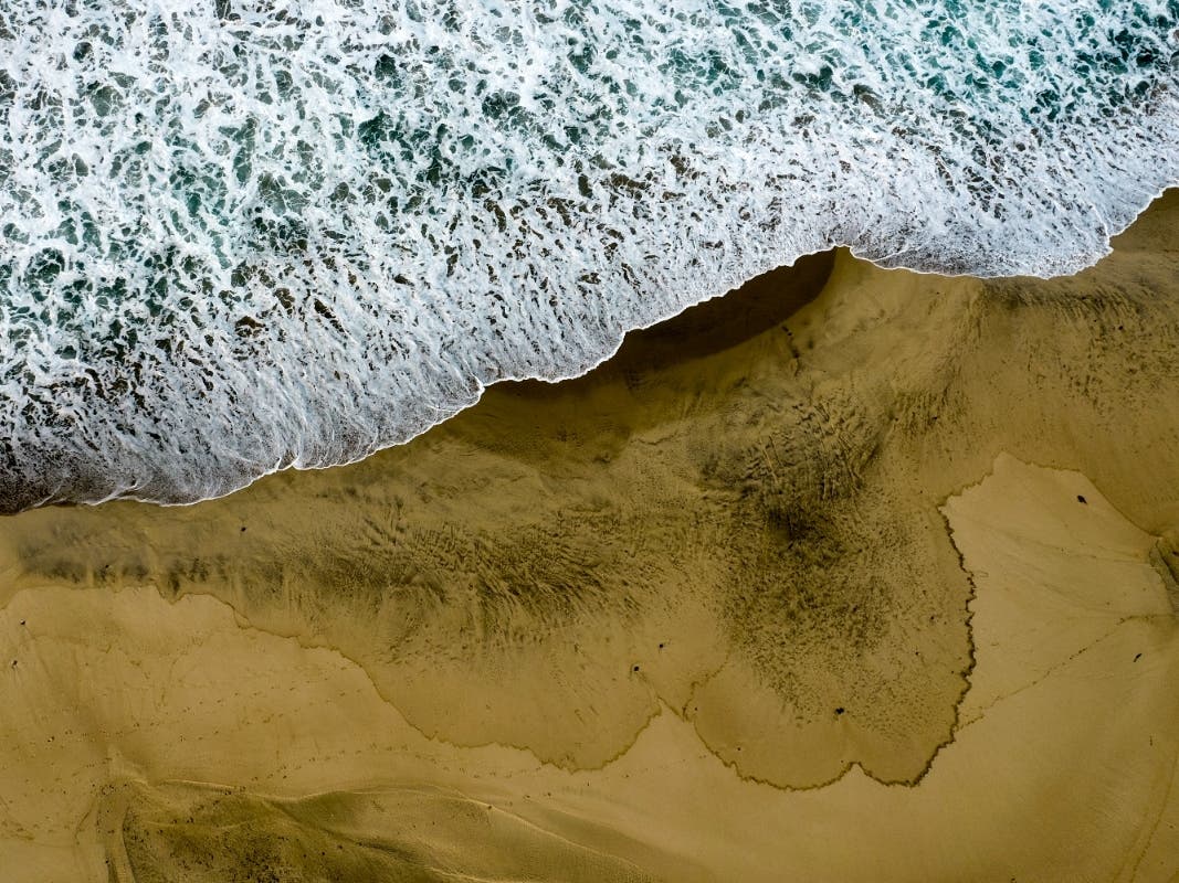 Oil washes up on the closed beach in Huntington Beach on Monday.