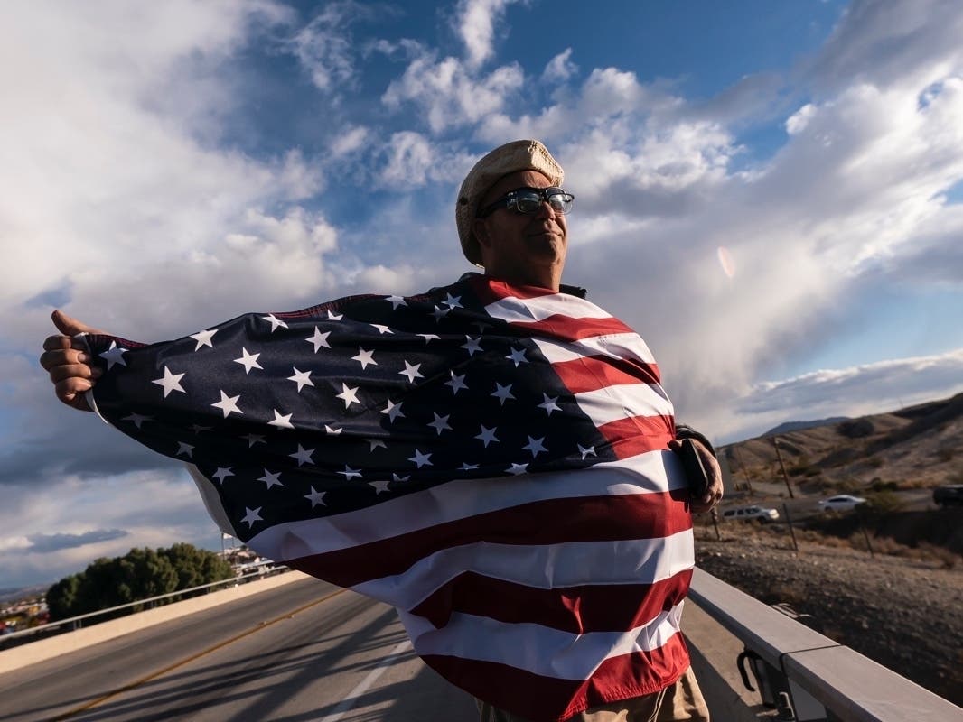 FILE - John Hiickman cheers on a convoy of truckers heading toward Washington to protest COVID-19 mandates, Feb. 23, 2022, in Needles, Calif. 