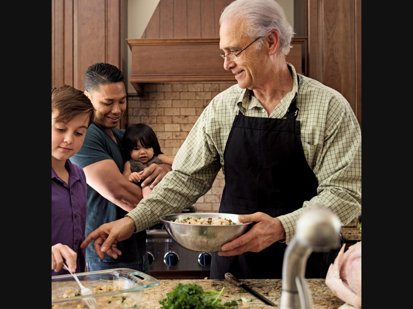 A person and their family preparing a meal in the kitchen.