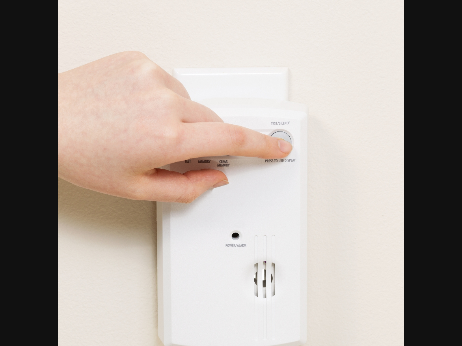 A person testing their carbon monoxide detector to make sure it's working.