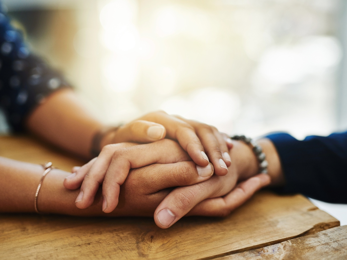 A person holding the hand of another in a caring manner to show their support and offer their help.