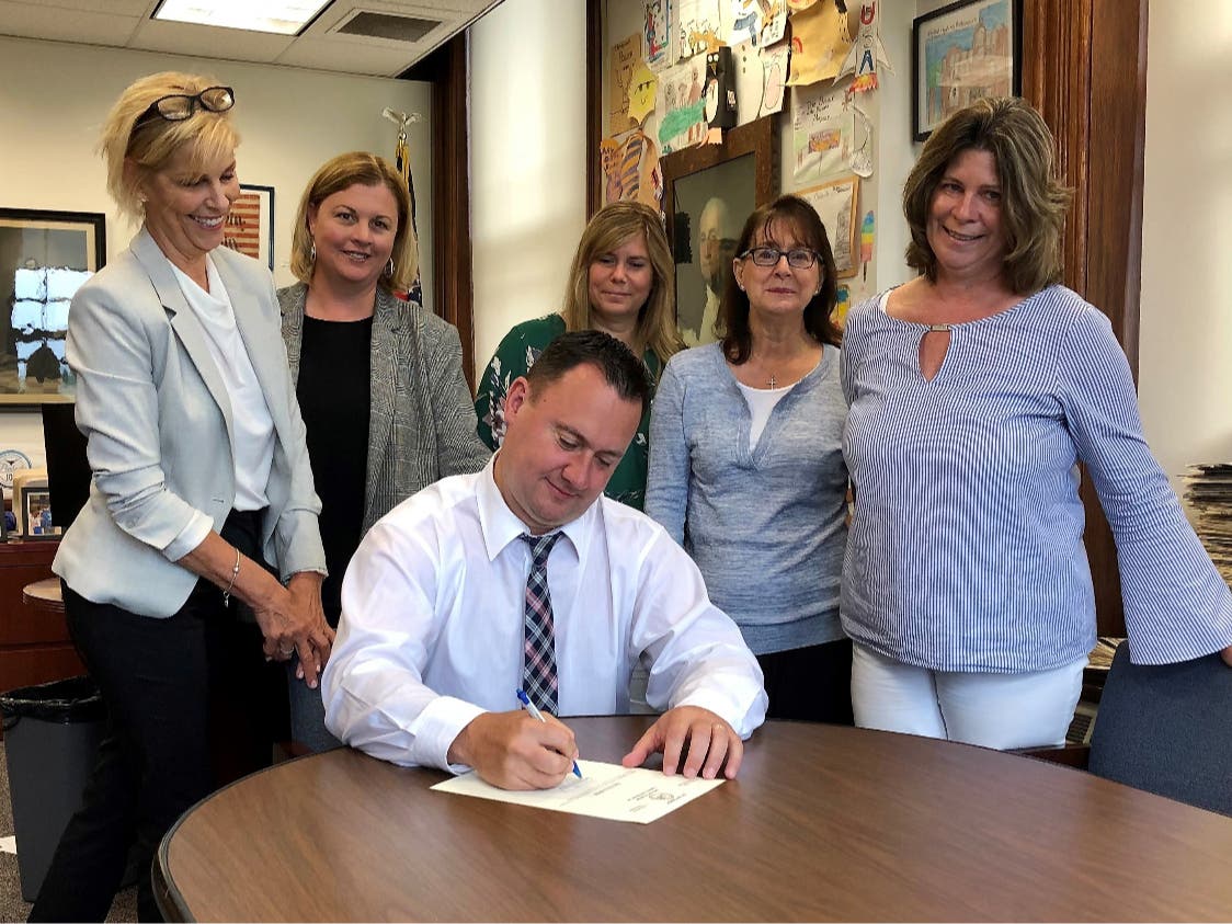 Mayor Ted Bettencourt signs an executive order lifting the city's State of Emergency, Standing, from left, Cathy Trombley, Beth Brennan O’Donnell, Kelly Bloom, Valerie Giacobbe and Darryl Ann McCarthy.