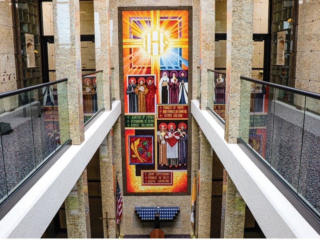 The Holy Name Chapel Mausoleum interior is adorned with colorful liturgical artwork, such as the Luminous mysteries and Corporal Works of Mercy. The chapel offers committal services, monthly Masses, spectacular courtyard atriums, and two-story balconies. 