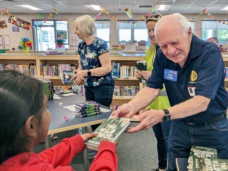 Rotarian Roy Porfido giving a book to Smith Elementary 3rd grader