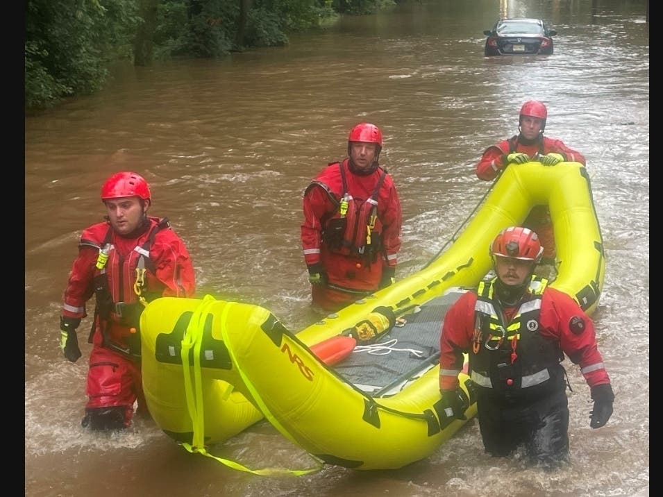 The rescuers walking back to dry land behind the high water truck after rescuing the family. The car can be seen in the background. 
