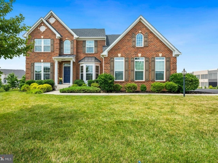 An Ashburn home for sale with tons of natural light has UV shades, an imposing foyer, and hardwood stairs with iron balusters. 