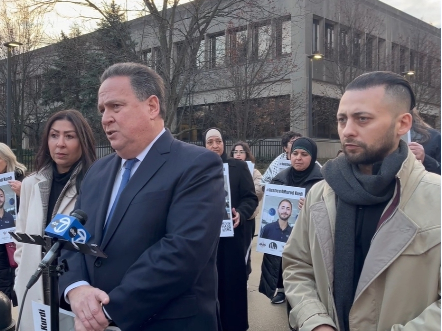 The family's private attorney, David Petrich, and Murod Kurdi's mother, Fadia Muhamad, and his brother, Suphi Kurdi, address news media in front of the Bridgeview Courthouse. 