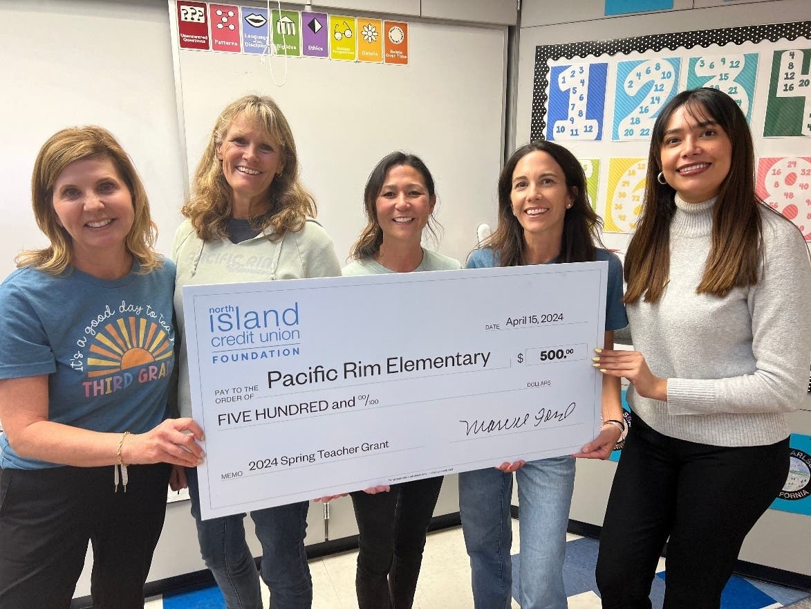 L-R: Carlsbad's Pacific Rim Elementary School teachers Barb Nelson, Anne Hampton, Jessica Hamabe and grant recipient Jamie Cozens receive a check from North Island Credit Union's senior school and community development officer Nancy Banuelos.