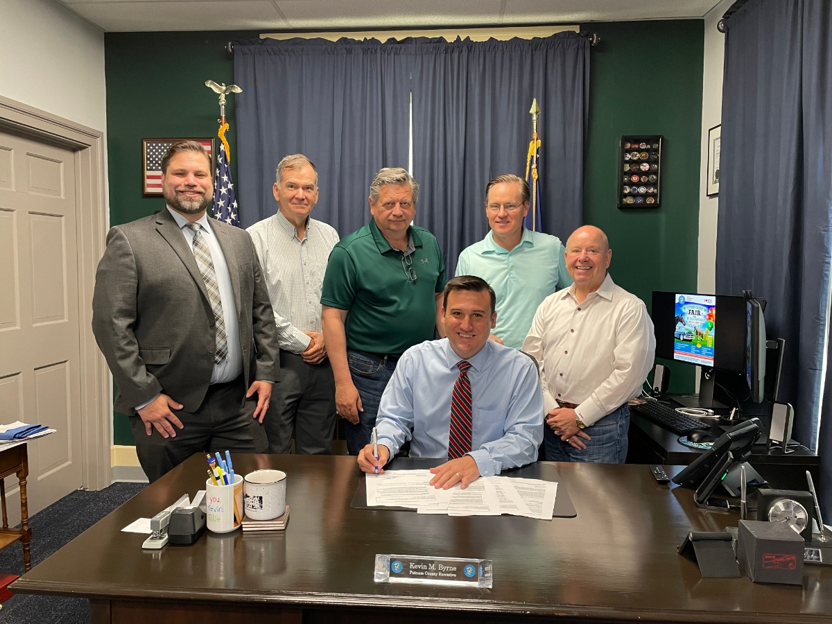 L to R: Senior Deputy County Attorney Conrad Pasquale, Director of IT Tom Lannon, Chairman of the County Legislature Paul Jonke, County Executive Kevin Byrne (seated), Commissioner of DGS John Tully, and Deputy County Executive Jim Burpoe