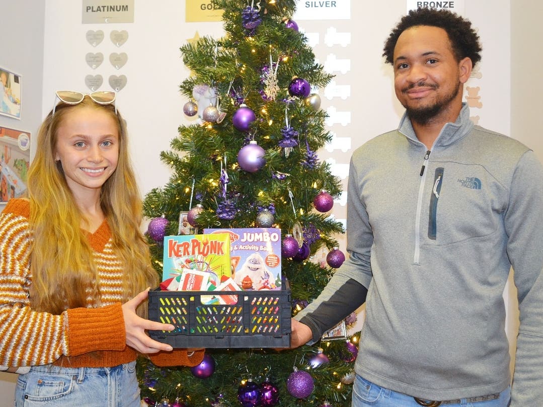 Oak Forest resident and Moraine Valley Nursing student Ashley Gallegos and friend Laron Atchison display a basket of toys for children fighting cancer at the Treasure Chest Foundation warehouse.