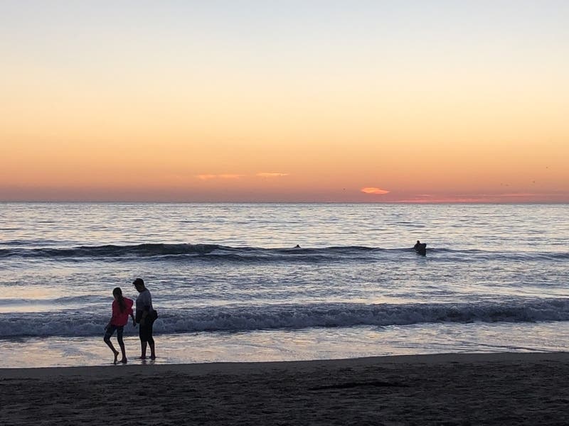 People walk along the beach at sunset in Venice, California.