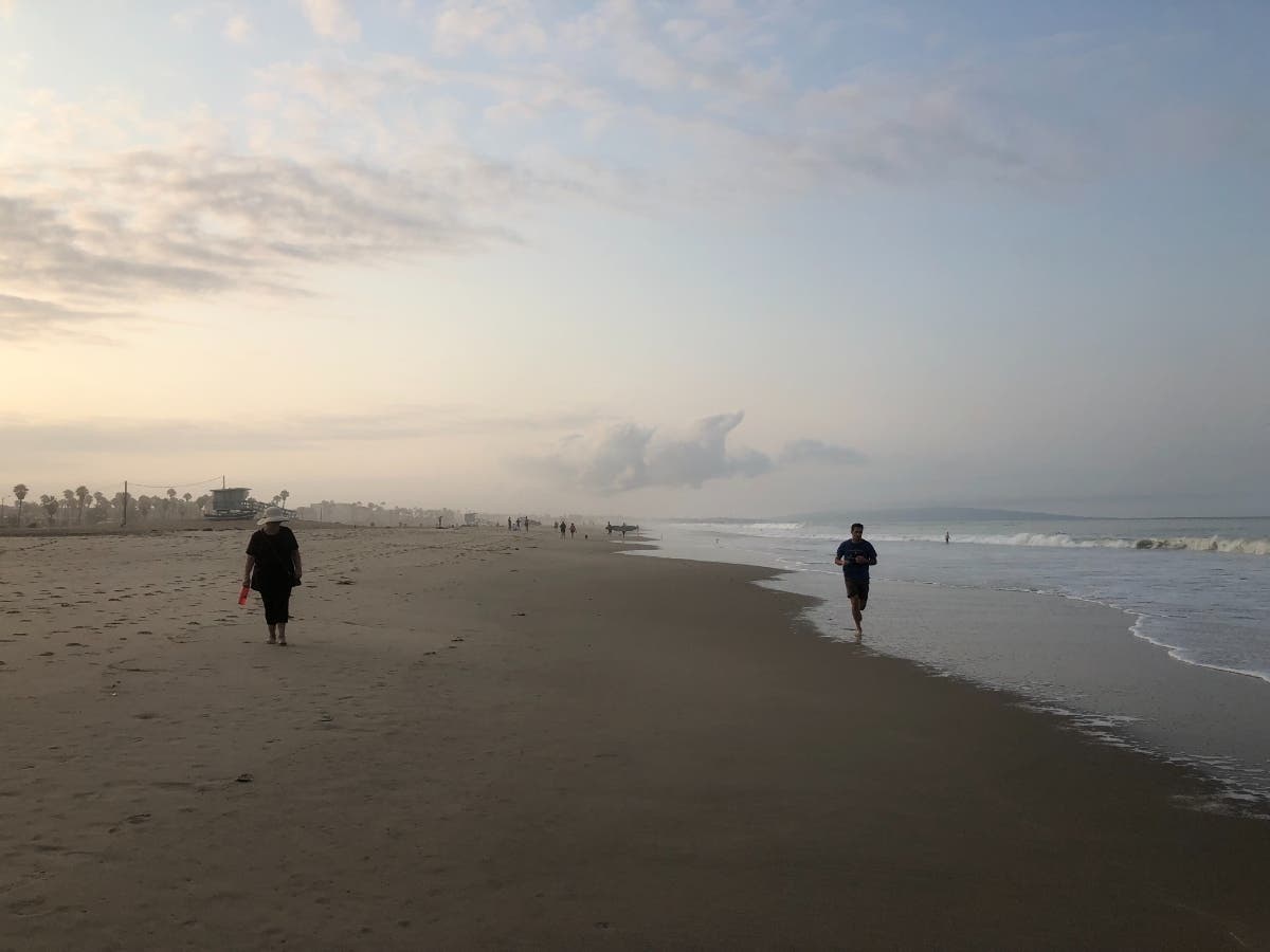 People walk and jog along the coast in Santa Monica, California.