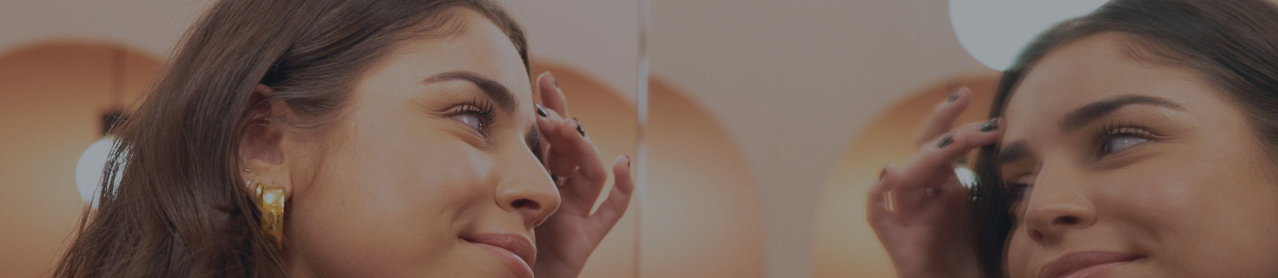 Woman looking in mirror and touching forehead with hand