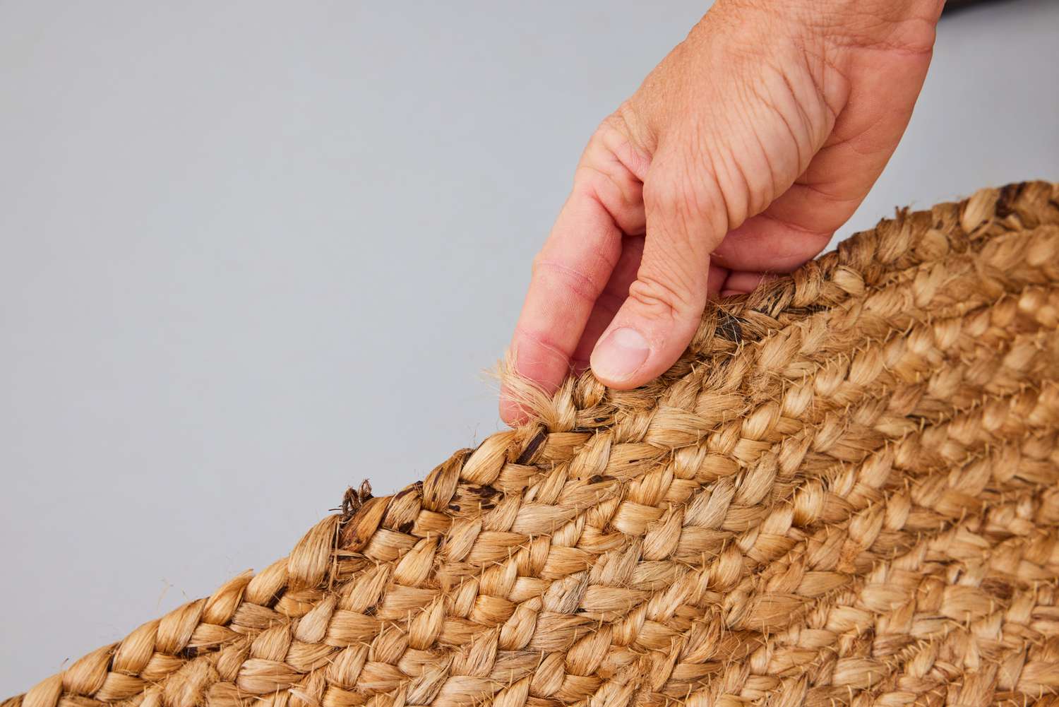 A person touches the nuLOOM Rigo Hand Woven Jute Area Rug