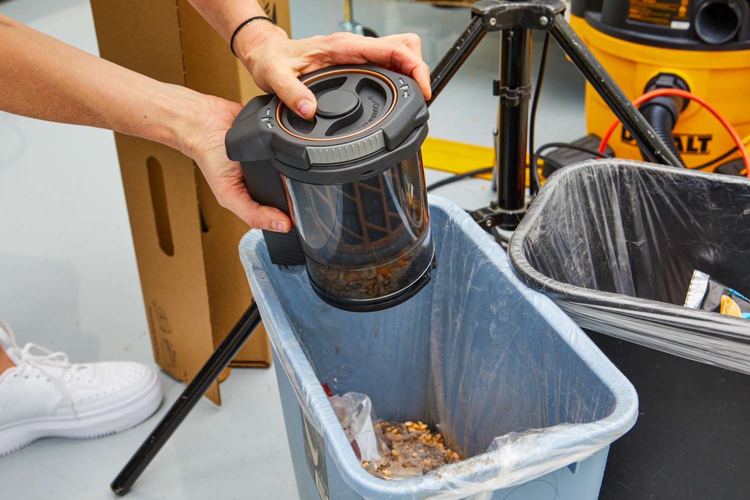 Person emptying the Miele Triflex HX2 Cat & Dog Vacuum into a trash bin 