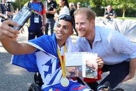 Prince Harry, Duke of Sussex takes a selfie with a winner at the cycling medal ceremony and and hands over a medal to the winning team at the Cycling Track during day six of the Invictus Games 