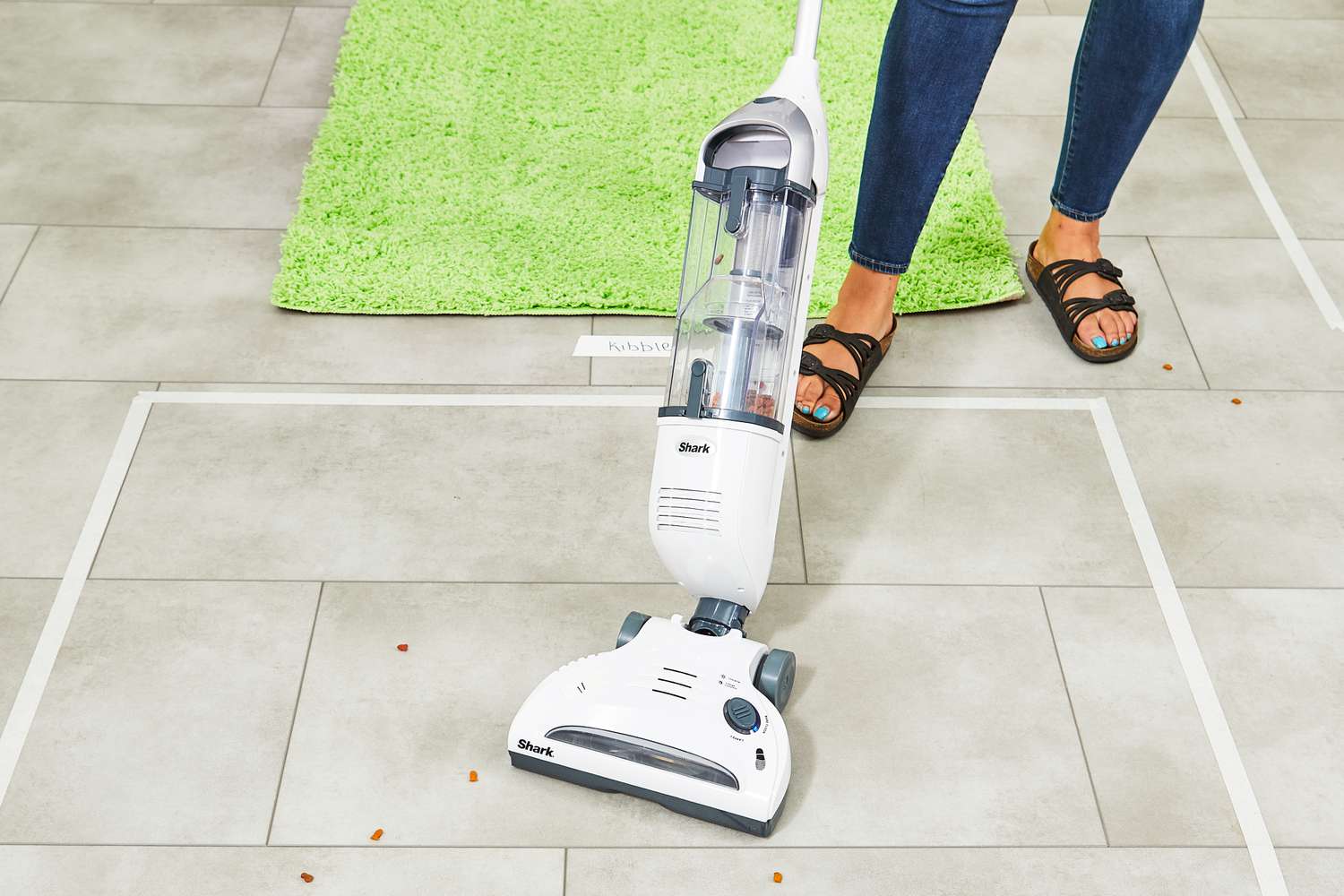A person using Shark Navigator Freestyle Cordless Upright Vacuum to clean up pieces of food on floor