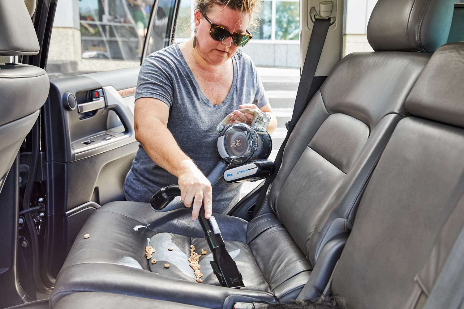 Person using Black+Decker Flex Cordless Handheld Vacuum to clean cereal from a car seat