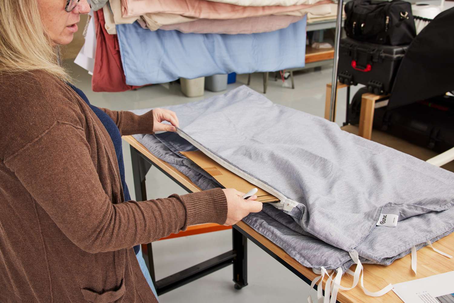 A person testing the Bare Home Duvet Cover that is partially folded on a work table. 