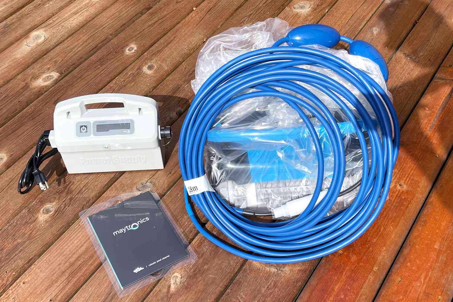 Dolphin Nautilus CC Plus Robotic Pool Cleaner bagged parts displayed on wooden deck