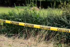 Stock Photo of Yellow Police Tape in a Rural Field