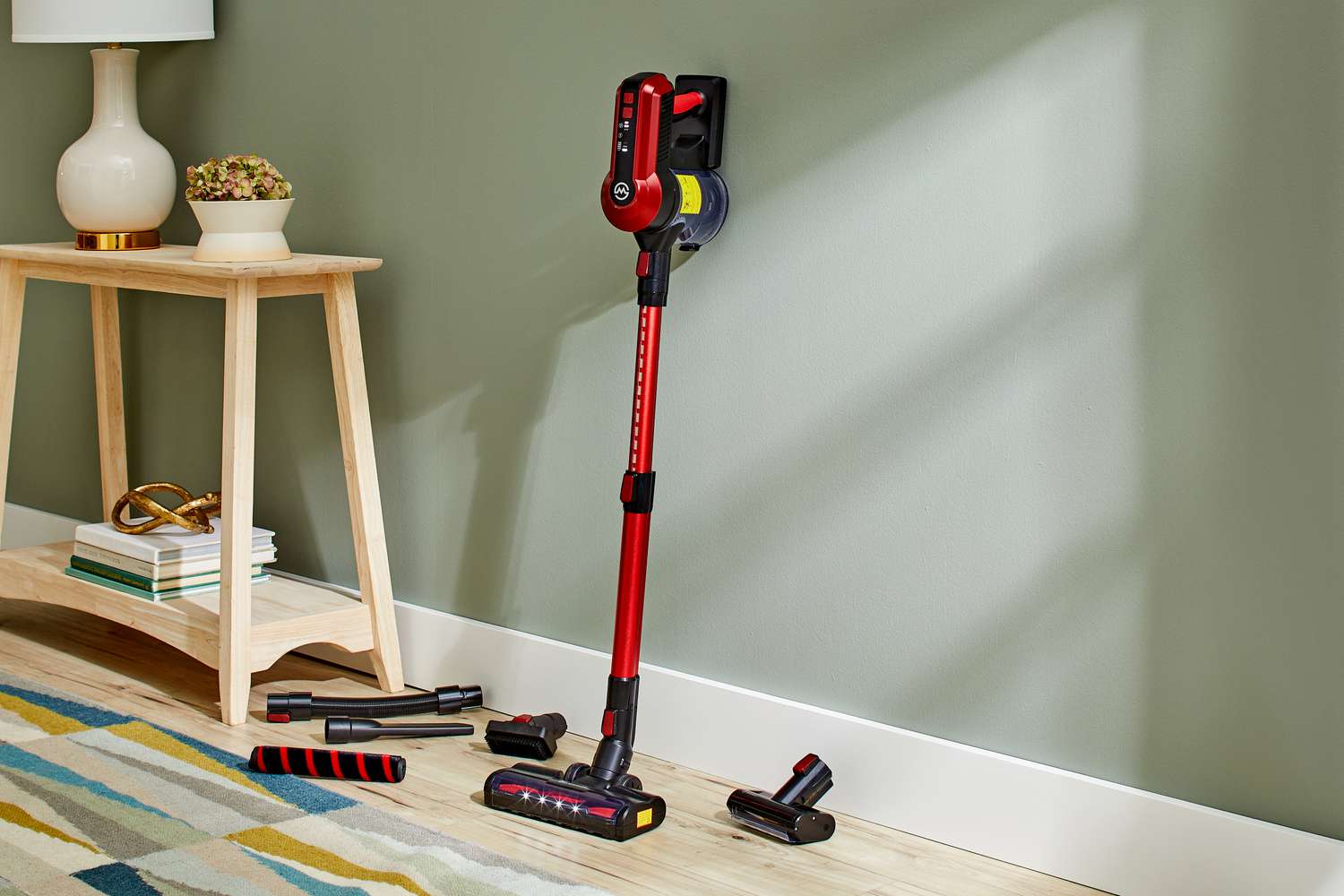 Moosoo Stick Vacuum Strong Suction Cordless leaning against a wall next to attachments 