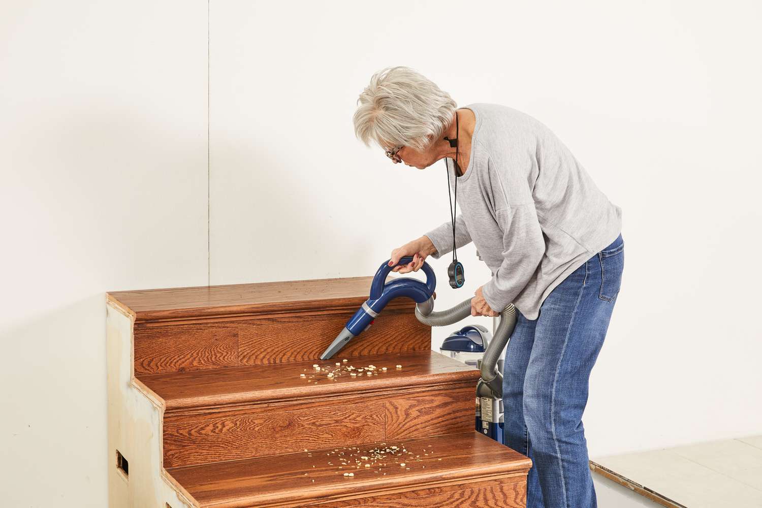 Person using a Shark NV360 Navigator Lift-Away Deluxe Upright Vacuum to clean food from steps