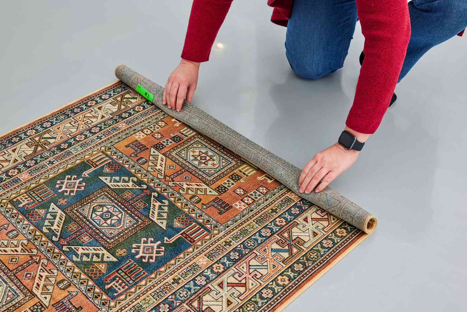 A person rolls up the AllModern Ovid Rug